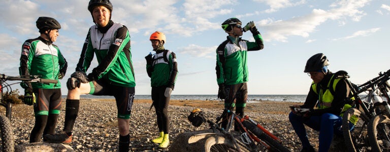 Fem manliga cyklister tar en paus i solnedgången på Ekstakusten.