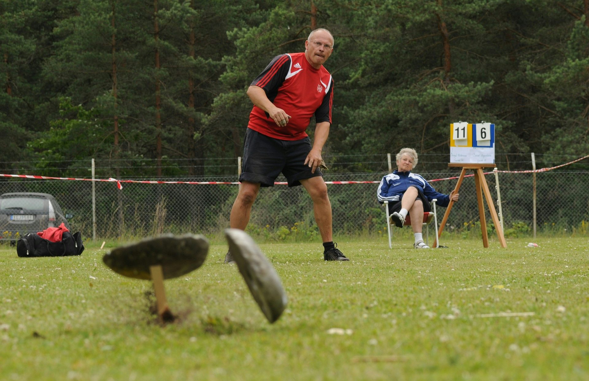 Man kastar varpa på Stångaspelen på Gotland. Kvinna i bakgrunden håller ordning på poängställningen i matchen. Det är sommar.