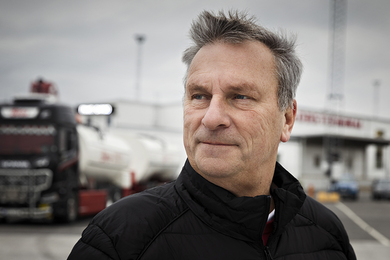 Peter Lindström, braschföreträdare från Åkeriföretagen på Gotland står på en parkeringsplats med lastbilar i bakgrunden