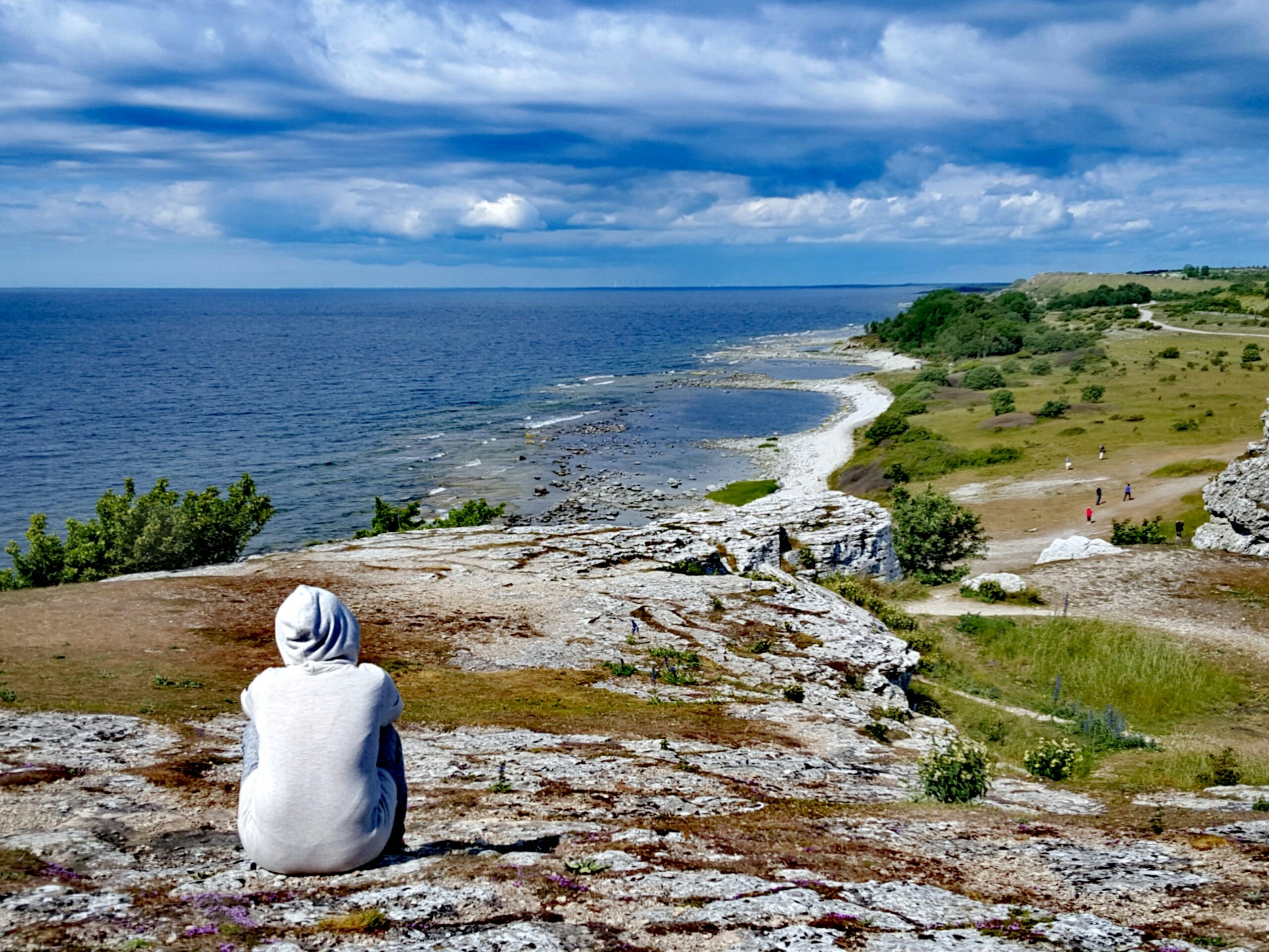 Pojke sitter på klipprna vid Hoburgen med vacker utsikt över Storsudret