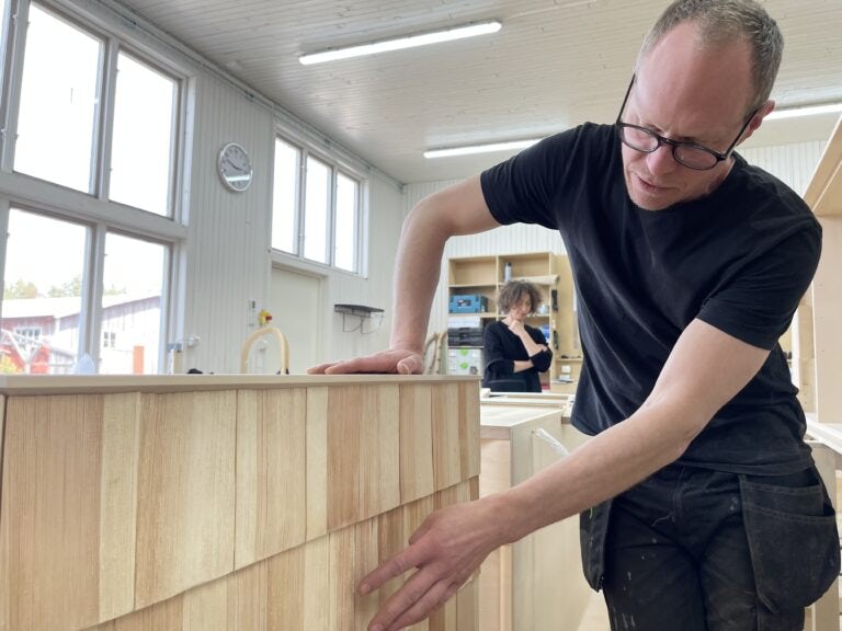 Lukas Dahlén visar en av företagets möbler och Leila Abh Alwaheb pratar med en av snickeriets medarbetare.